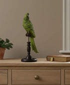 Decorative green parrot figure on a wooden stand with a plant and book in the background.