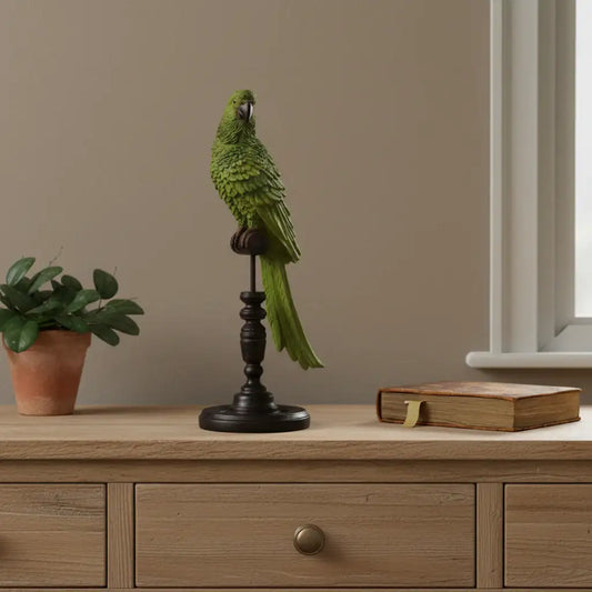 Decorative green parrot figure on a wooden stand with a plant and book in the background.