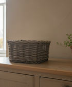 Wicker basket and potted plant on a wooden surface near a window.