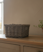 Wicker basket on a wooden surface with a plant in the background
