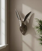 Metallic rabbit head wall decoration on a plain wall.