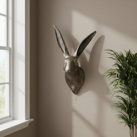Metallic rabbit head wall decoration on a plain wall.