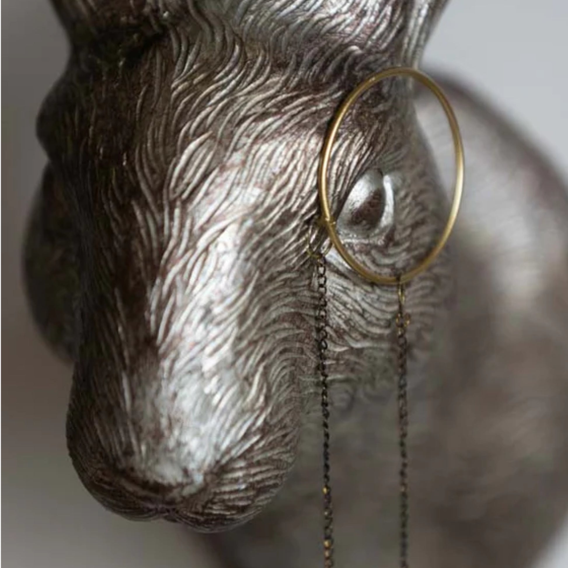 Decorative wall hook shaped like a deer head with a magnifying glass on a neutral background