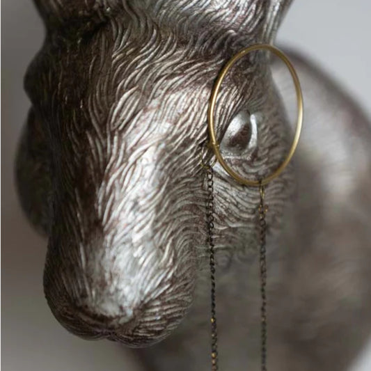 Decorative wall hook shaped like a deer head with a magnifying glass on a neutral background