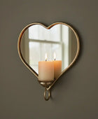 Heart-shaped mirror with candle holder on a brown wall