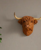 Faux leather Highland cow head wall decoration on a plain wall.