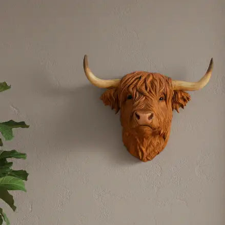 Faux leather Highland cow head wall decoration on a plain wall.