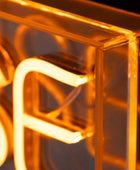 Close-up of a glowing amber neon-style sign with translucent acrylic or glass panels forming the letters 'S' and 'F'.