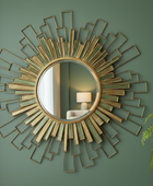 Decorative wall mirror with geometric design on a green wall