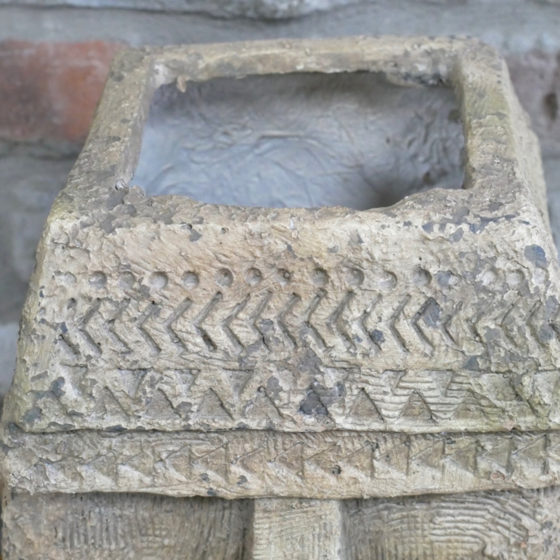 Decorative stone box with geometric patterns on a textured background