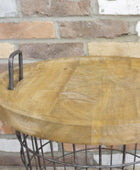 Wooden table with metal base against a brick wall