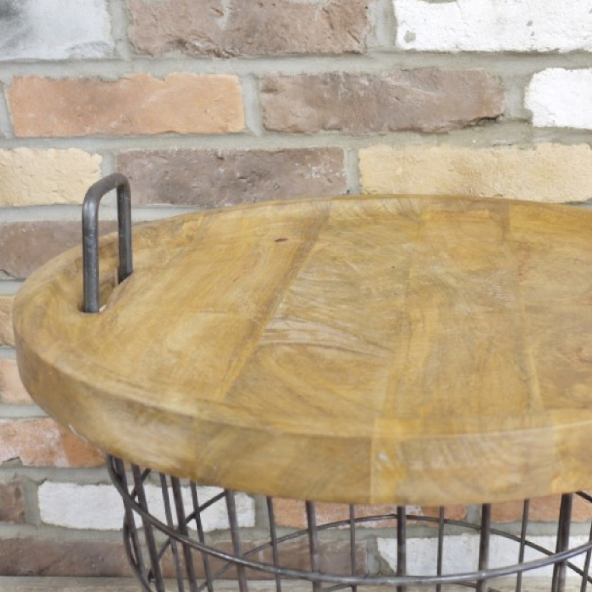 Wooden table with metal base against a brick wall