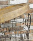 Wooden shelf with metal wire basket against a brick wall.