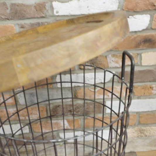 Wooden shelf with metal wire basket against a brick wall.