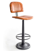 A modern industrial-style bar stool with a curved, ribbed cognac brown faux-leather seat and backrest, supported by a black metal swivel base with a footrest ring, on a white background.
