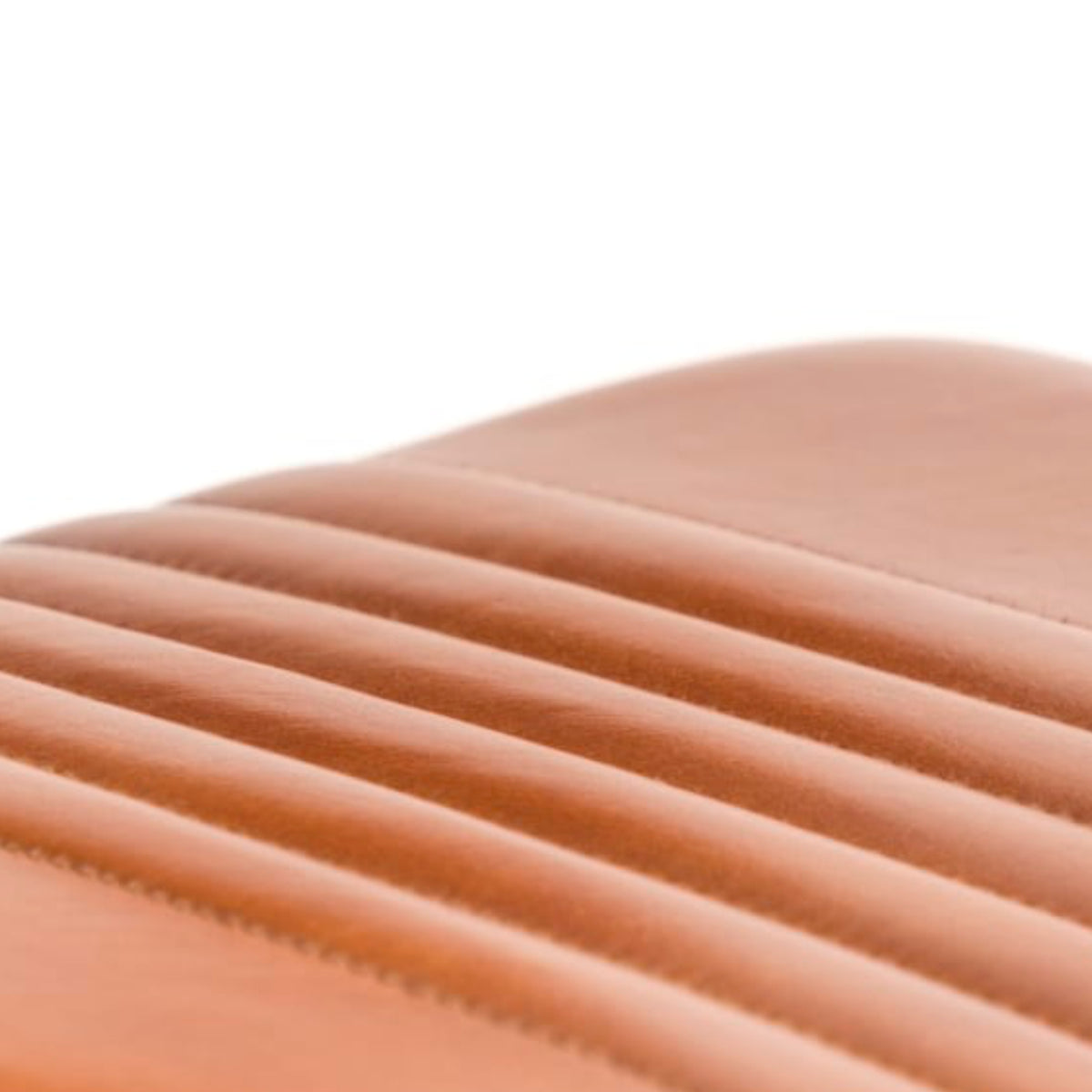 Close-up of a curved, ribbed leather surface in a warm tan or cognac brown color against a white background.
