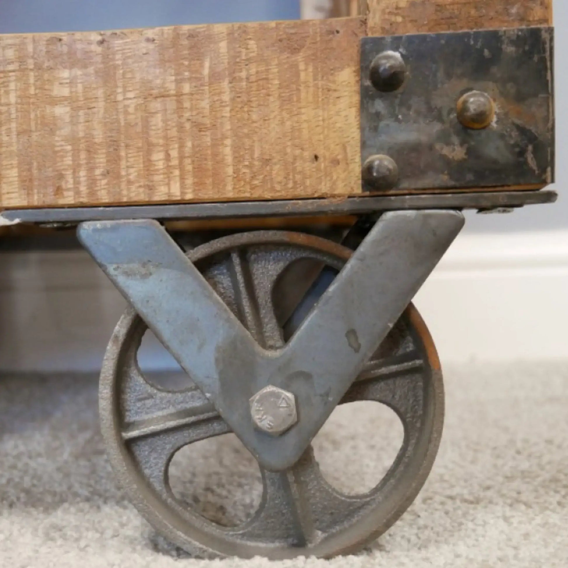 Wooden table with metal wheels on a carpeted floor