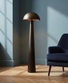 Modern floor lamp next to a blue armchair in a room with sunlight streaming through a window.