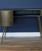 Bronze desk with a black shelf against a gray wall.