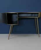 Modern black desk with gold legs against a blue wall
