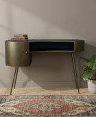 Modern desk with gold accents in a room with a patterned rug and plant.