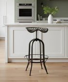 Black metal stool in a modern kitchen with white cabinets and wooden floor.