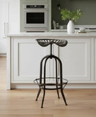 Black metal bar stool in a modern kitchen with white cabinets and wooden floor.