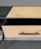 Wooden desk with a black metal frame and drawer handle, on a gray floor.