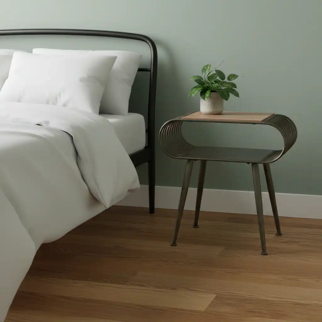 Bedroom with a bed, nightstand, and plant against a green wall.