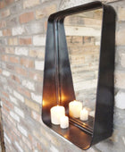 Decorative wall mirror with candles inside, mounted on a brick wall.