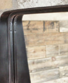 Close-up of a metal frame with a reflective surface against a textured wall.