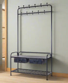 Black metal coat rack with hooks and a shelf against a light green wall.