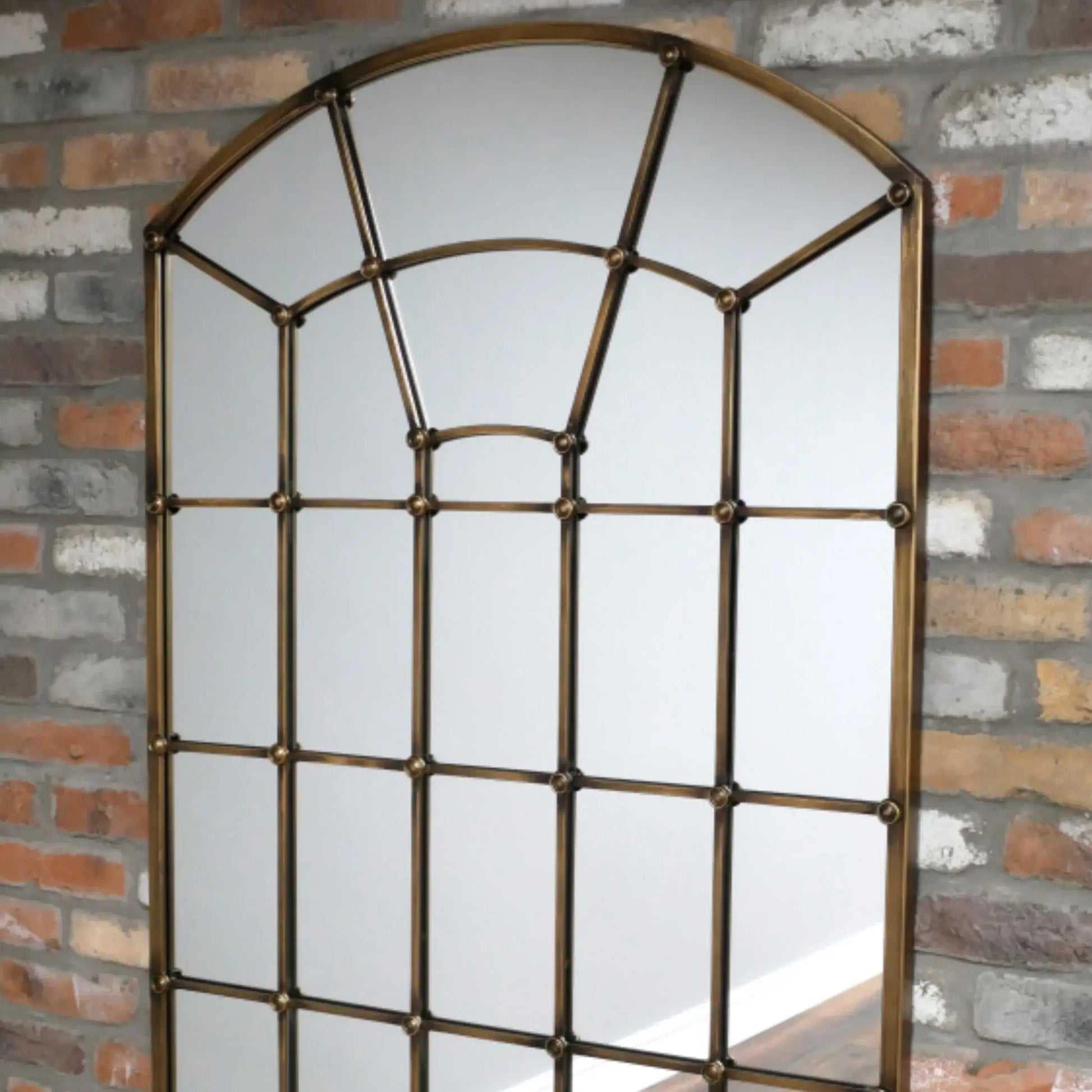 Decorative mirror with a grid design on a brick wall background