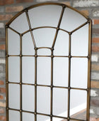Decorative mirror with a grid design on a brick wall background