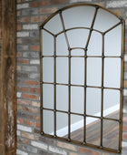 Decorative window-style mirror on a brick wall