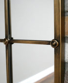 Decorative metal frame with glass panel against a stone wall.