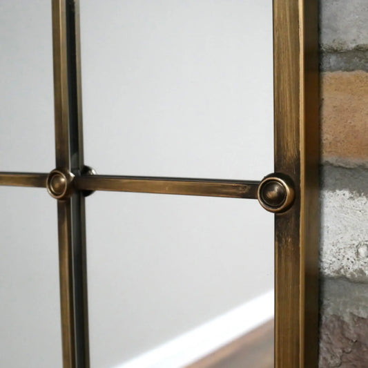Decorative metal frame with glass panel against a stone wall.