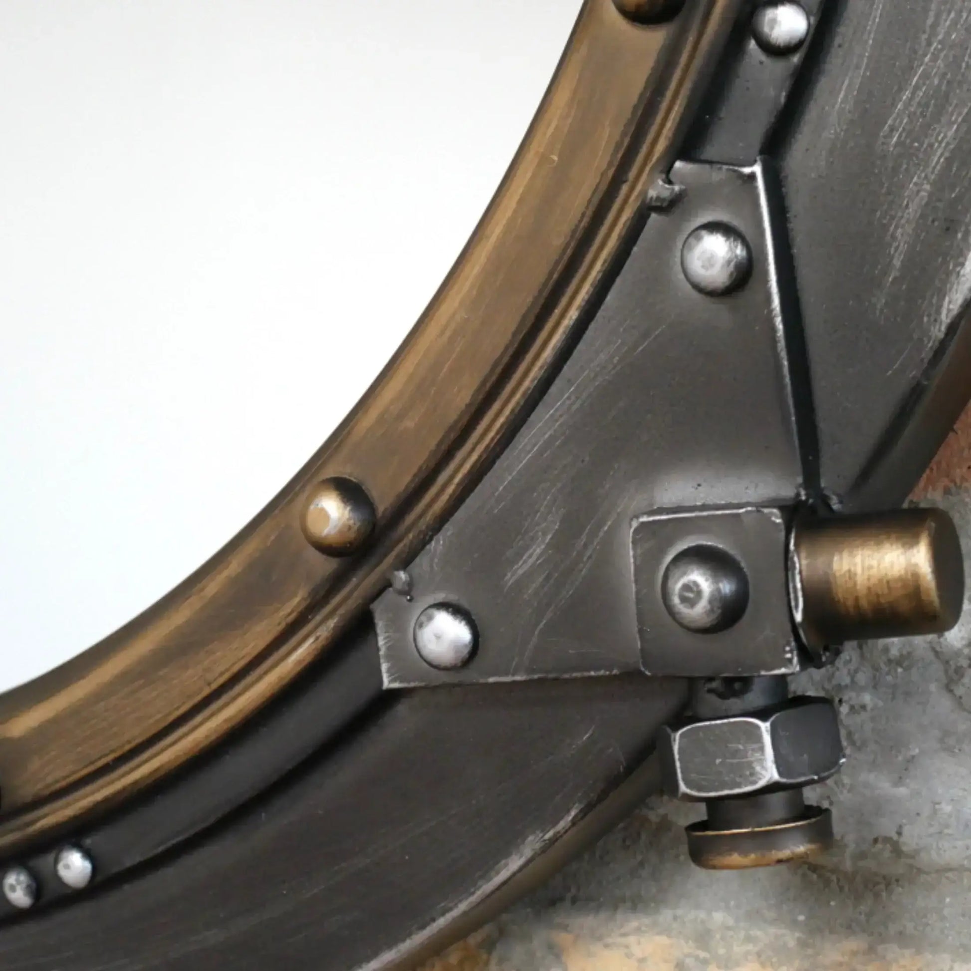 Close-up of a metal object with circular component and bolts on a gray background