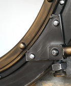 Close-up of a metal object with circular component and bolts on a gray background