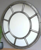 Round metallic mirror with a vintage design on a brick wall