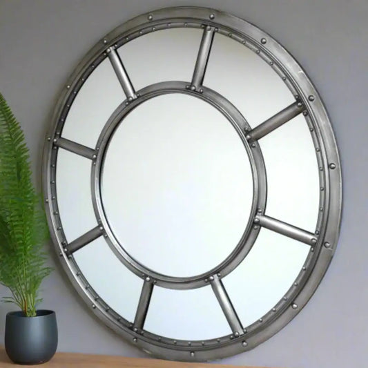 Round metallic mirror with a vintage design on a brick wall