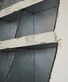 Rust-covered metal shelves in a corner with peeling paint.