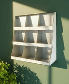 Metal wall shelf against a green wall with plant shadow