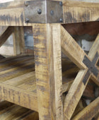 Rustic wooden side table with distressed natural wood finish, dark metal hardware, and X-brace support on a brick background.