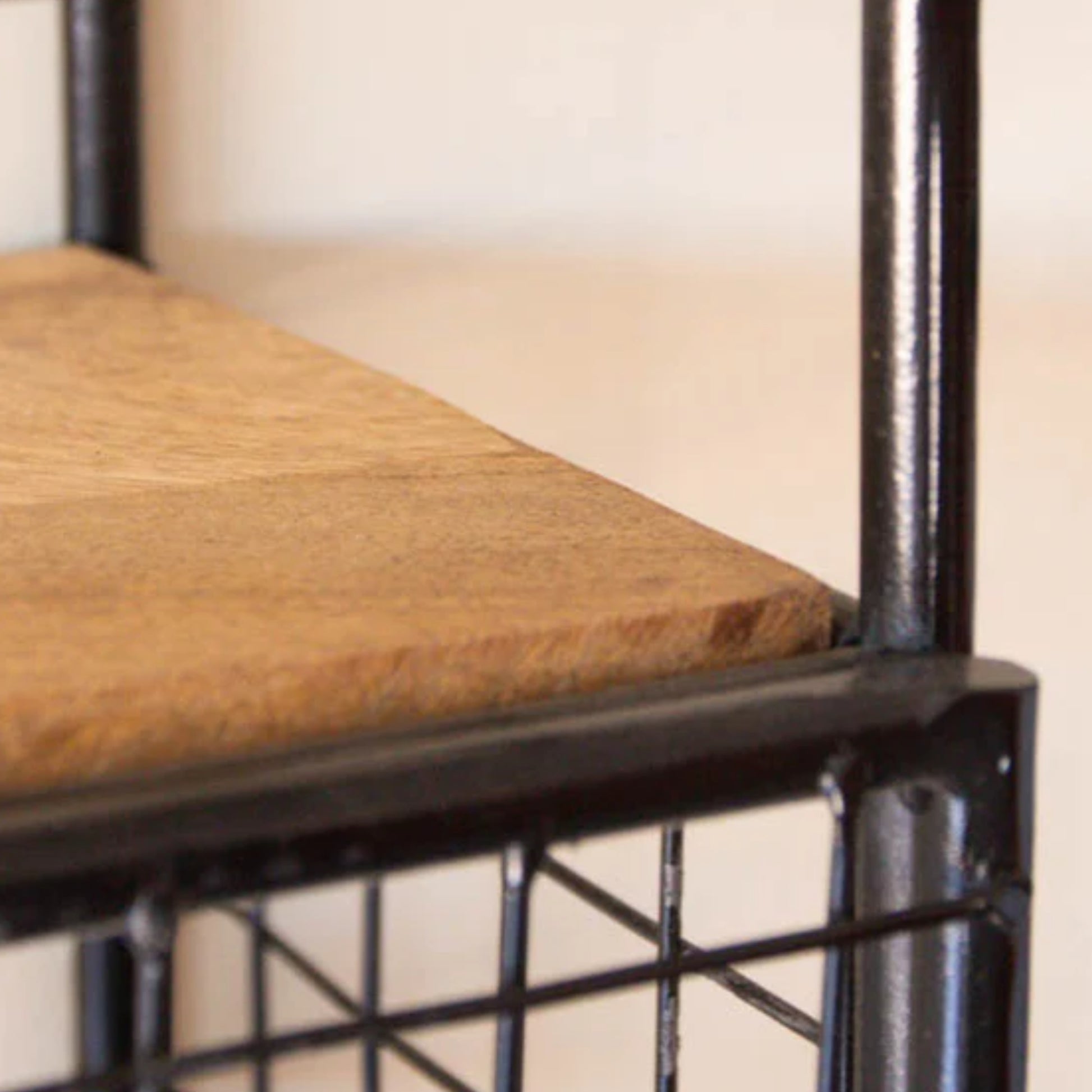 Close-up of a chair with a wooden seat and black metal frame.