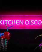 Neon sign reading 'KITCHEN DISCO' with decorative items on a dark background