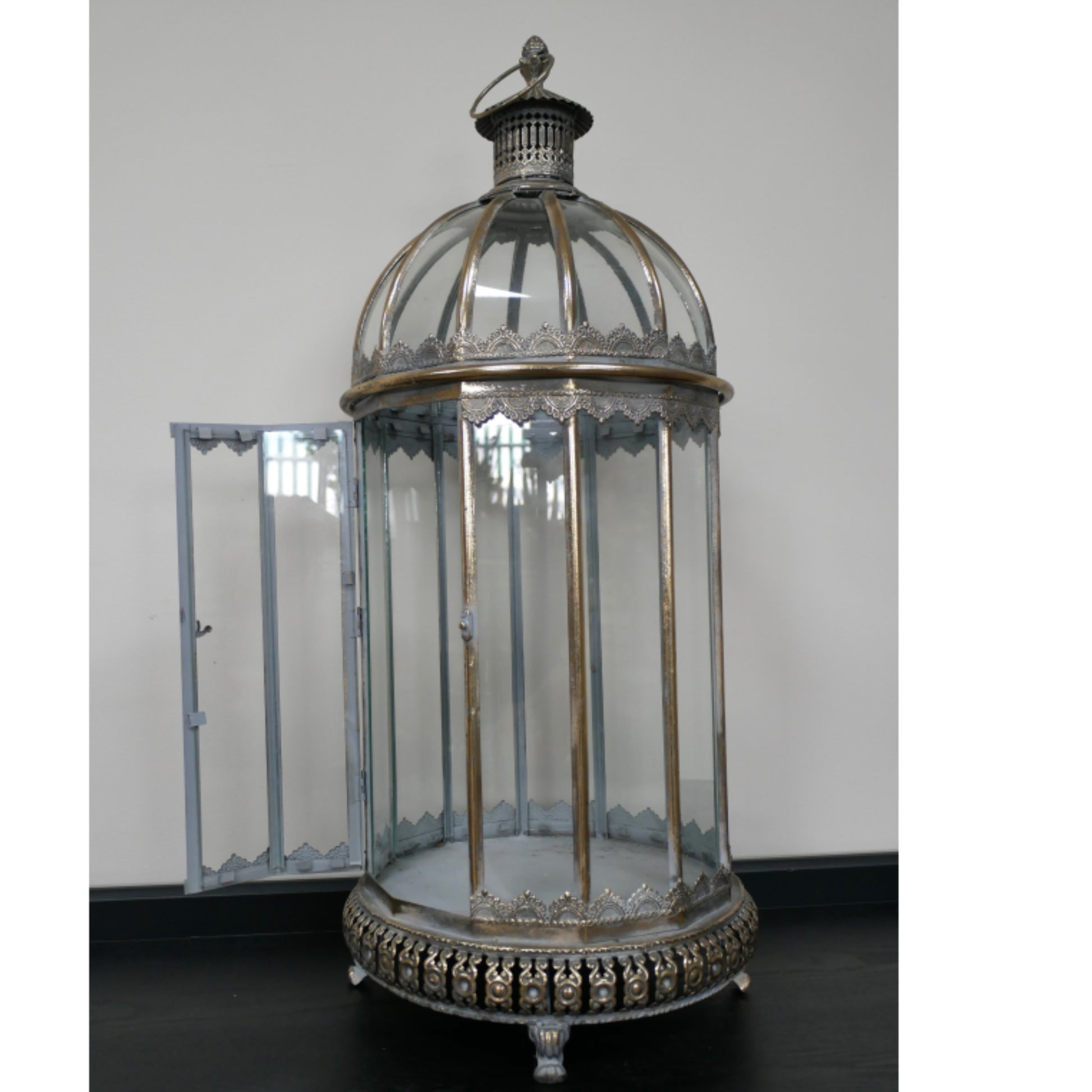 An ornate vintage-style birdcage lantern with a domed glass top, clear glass side panels, and an open side door, featuring an antique silver-toned metal frame and decorative base.