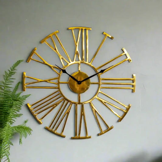 Gold wall clock with Roman numeral design on a white background