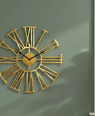 Gold wall clock with Roman numeral design on a green wall