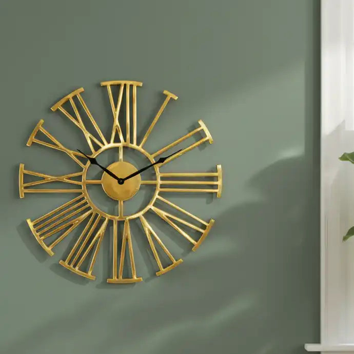 Gold wall clock with Roman numeral design on a green wall